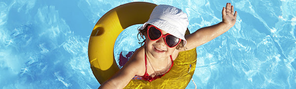Funny little girl swims in a pool in an orange life preserver