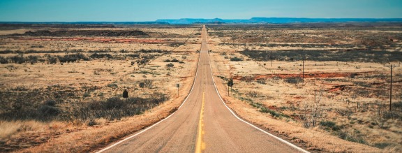 Long straight desert road stretching into the distance to the ho